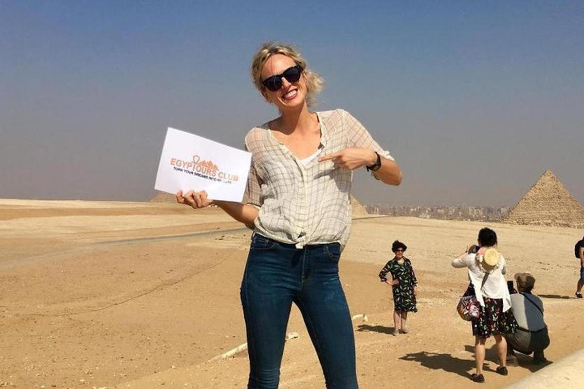 a woman holding a sign in front of the pyramids