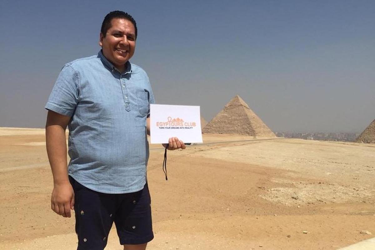 muž držící ceduli před pyramidami