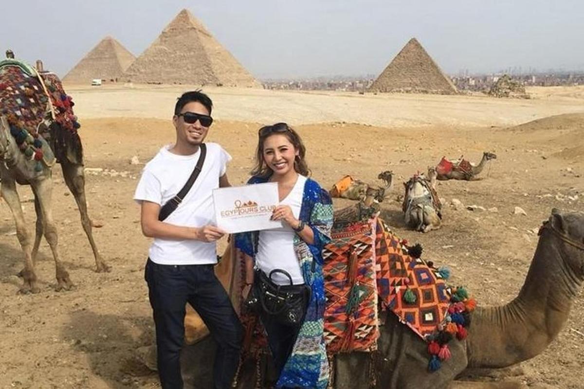 ein Mann und eine Frau halten ein Schild vor Pyramiden