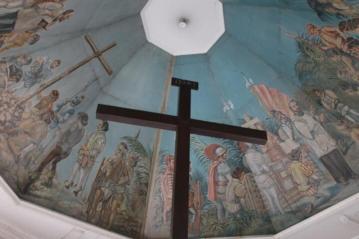 una cruz en el techo de una iglesia con un mural