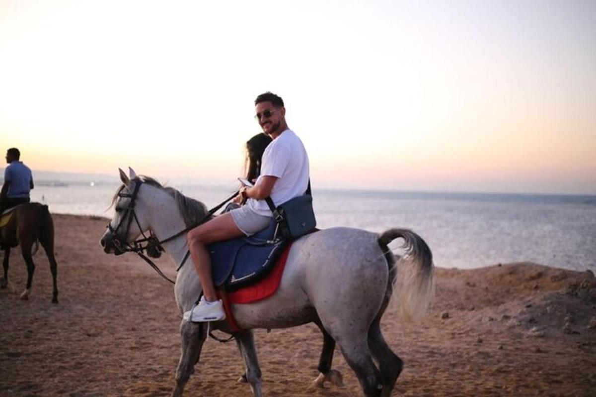 un home i una dona muntant a cavall a la platja