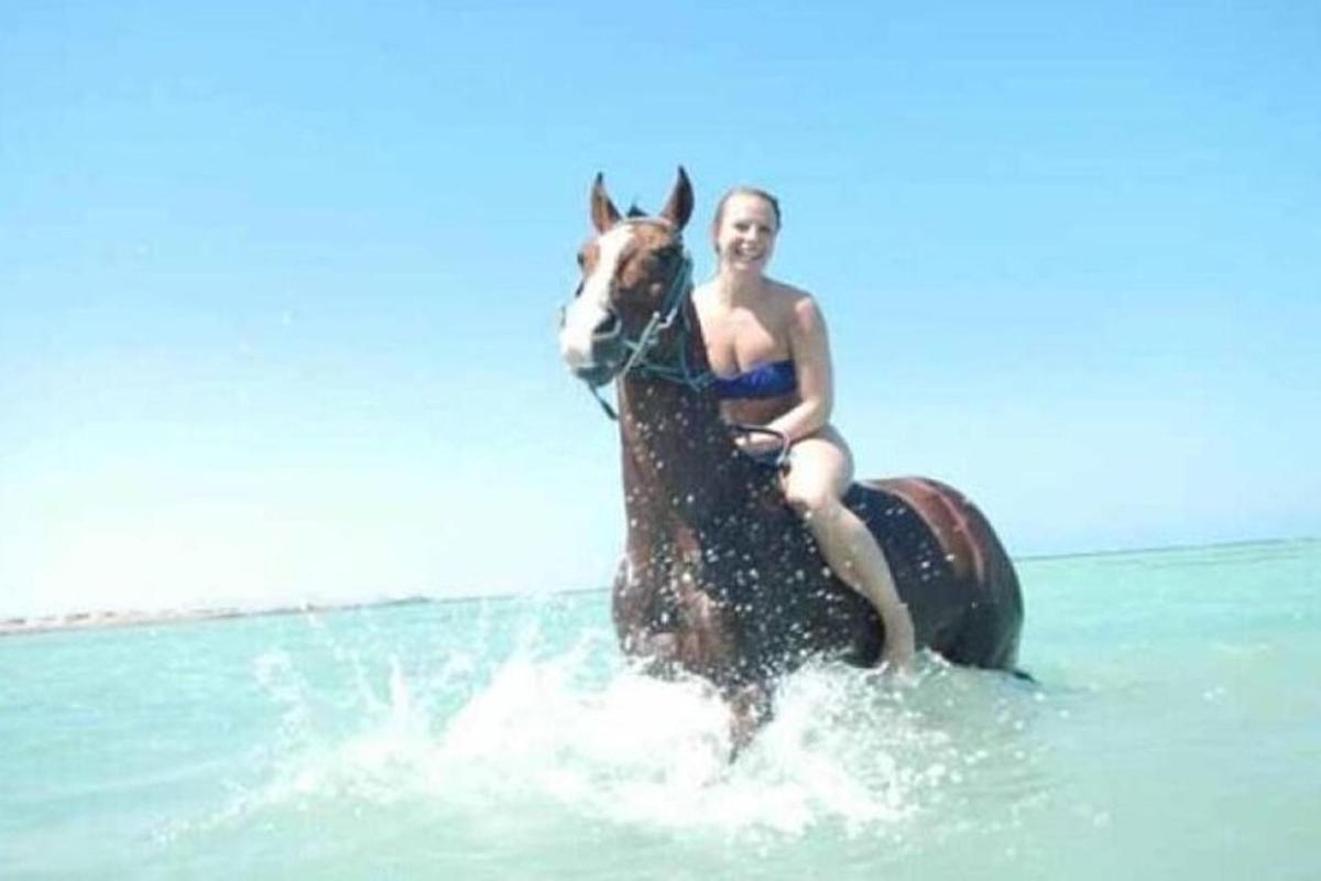 žena v bikinách jazdiaca na koni v oceáne