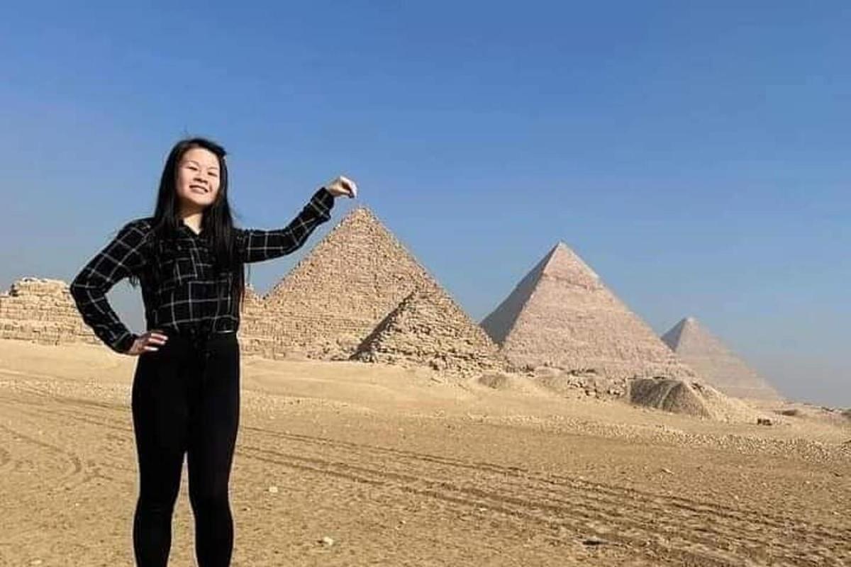 seorang wanita berdiri di hadapan piramid