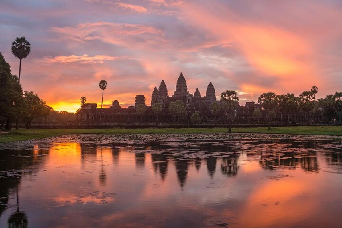 una posta de sol sobre un estany davant d'un temple