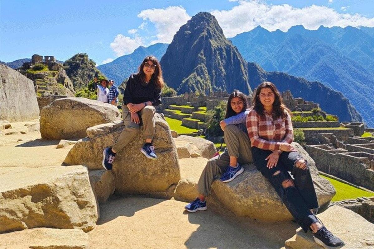 tiga wanita duduk di atas batu di puncak gunung