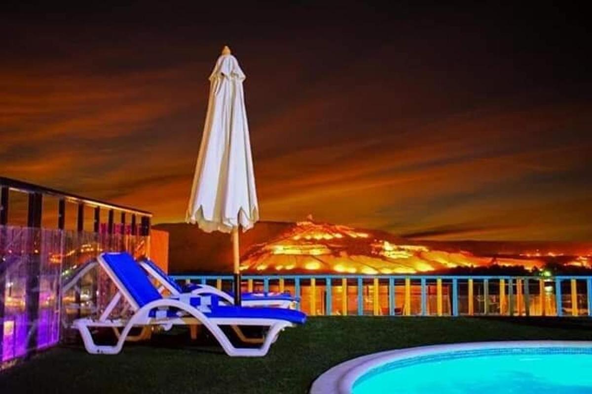 um par de cadeiras e um guarda-sol ao lado de uma piscina