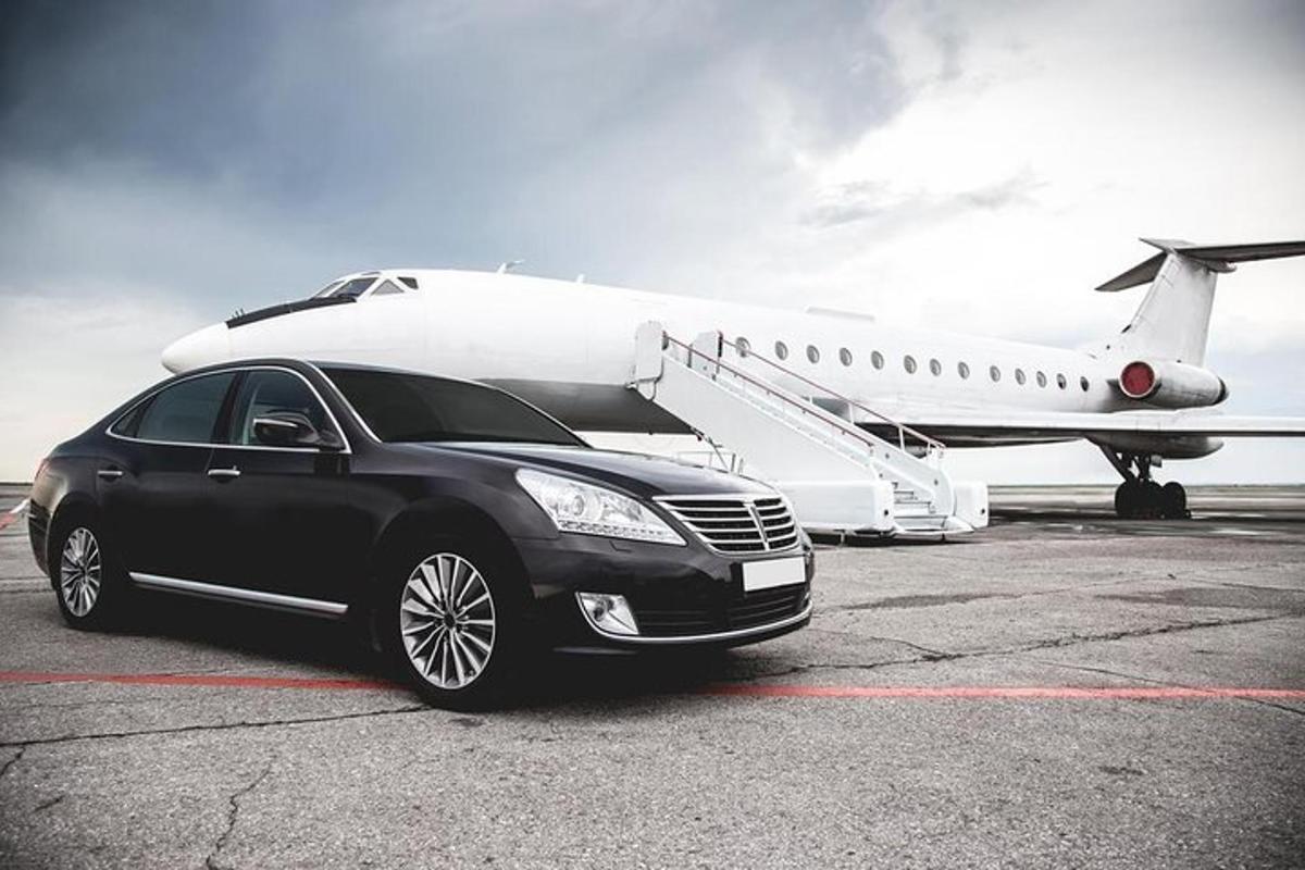 un'auto nera è parcheggiata accanto a un aereo