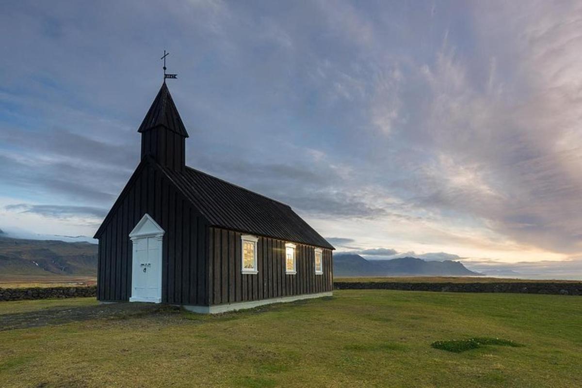 svört kirkja með hvítum dyrum í túni