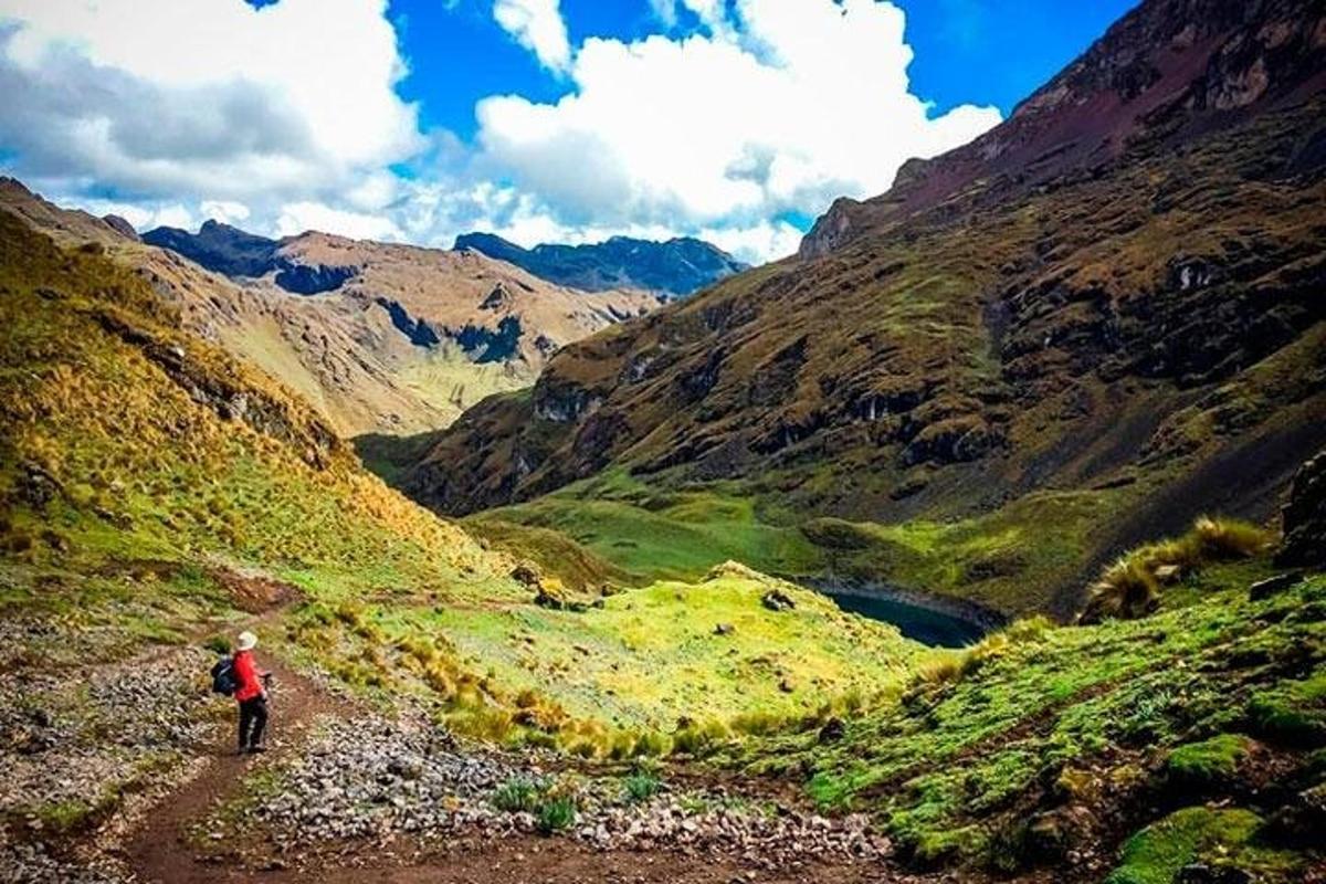 uma pessoa caminhando em uma estrada de terra através de um vale montanhoso