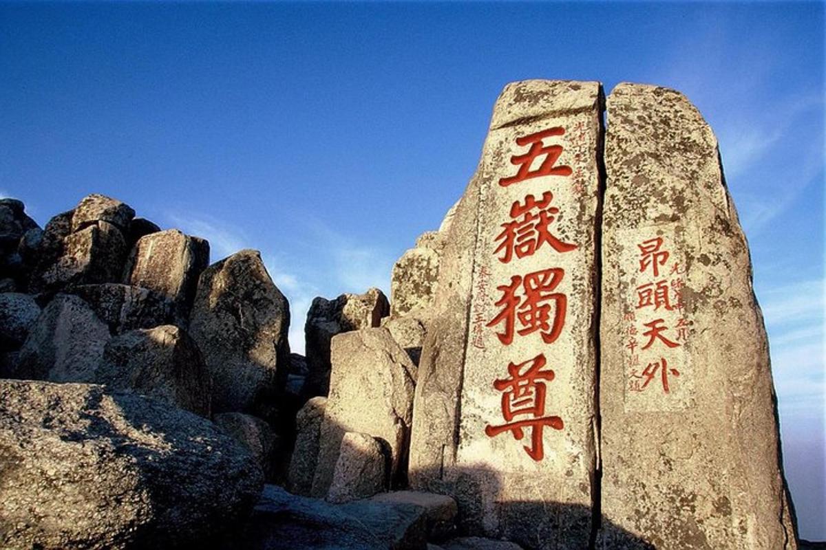 una roccia con una scritta cinese accanto ad alcune rocce