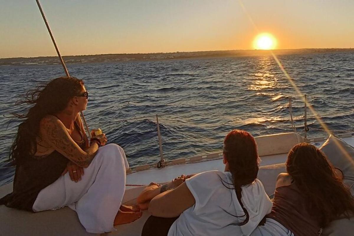 Tres mujeres sentadas en un barco mirando la puesta de sol