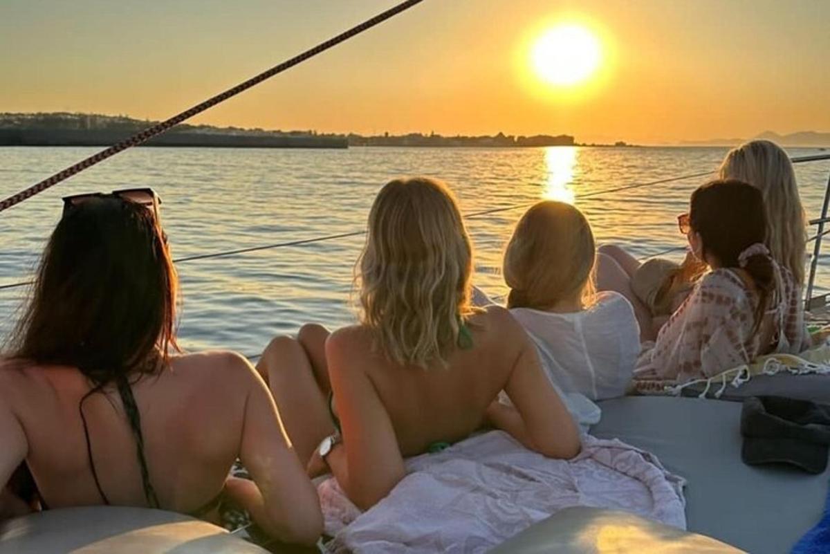 Un grupo de mujeres sentadas en un barco mirando la puesta de sol