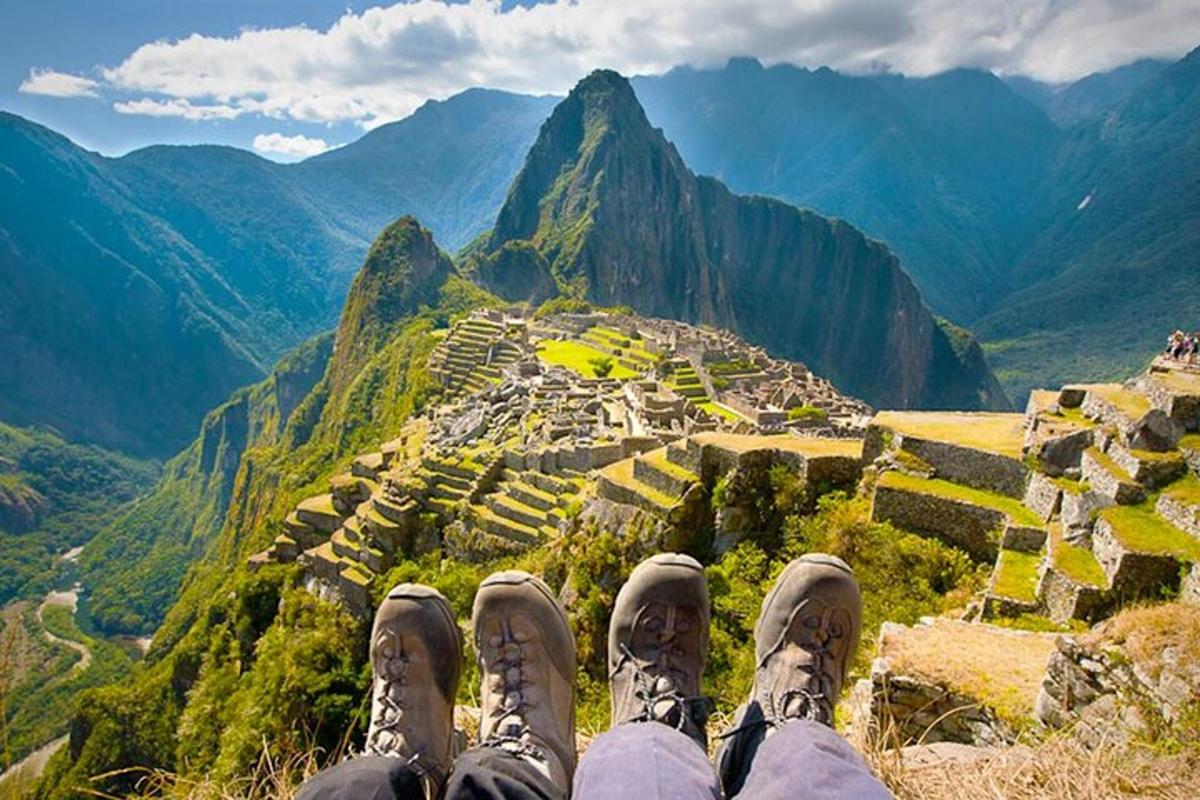 Una persona con los pies en lo alto de una montaña con vistas a una ciudad.