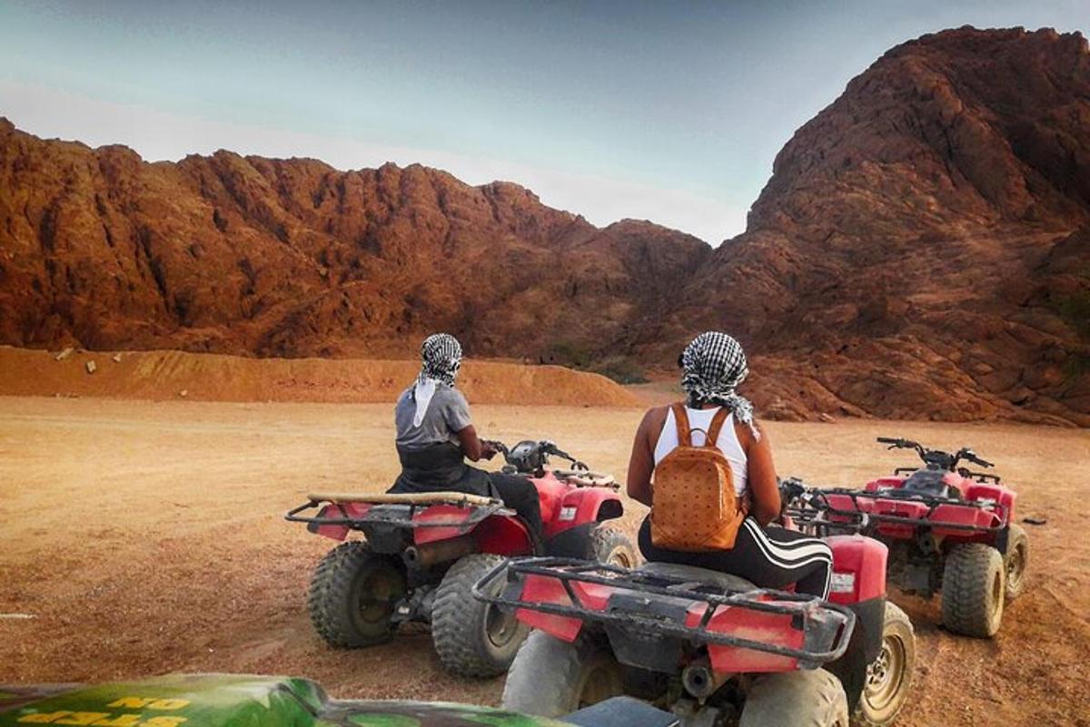due persone stanno guidando dei quad nel deserto