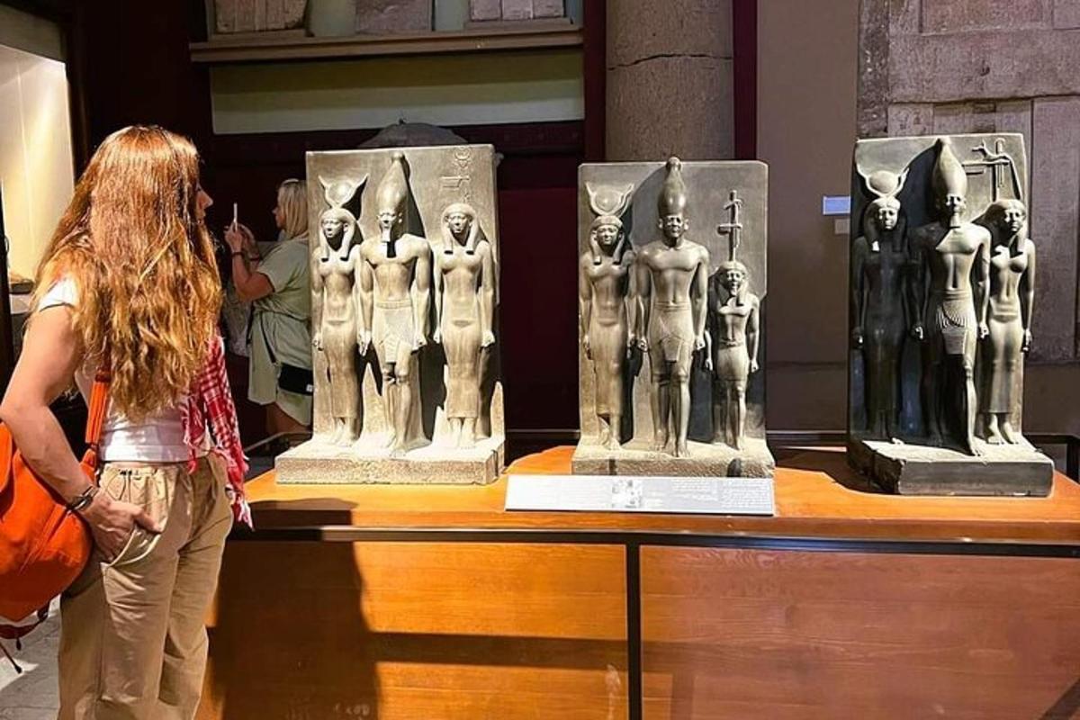 μια γυναίκα που στέκεται μπροστά σε μια έκθεση αγαλμάτων