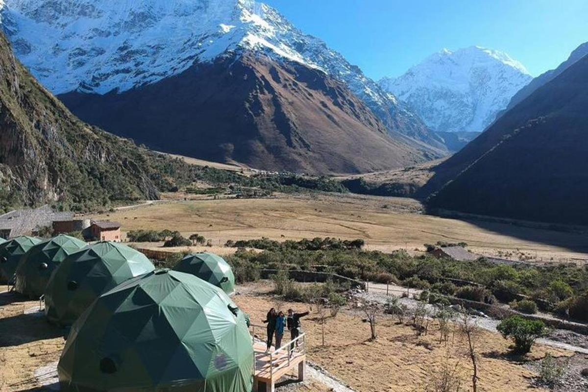 a group of tents in a field with a mountain
