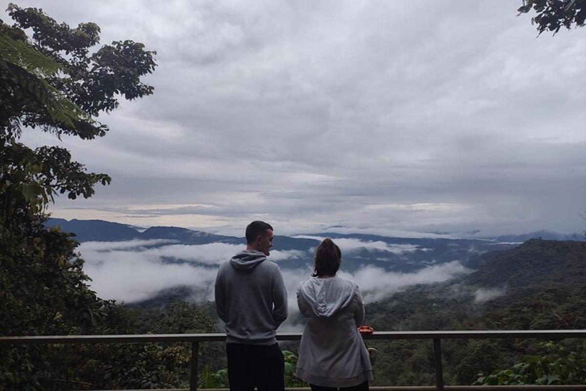 a man and a woman standing on a railing looking at the mountains