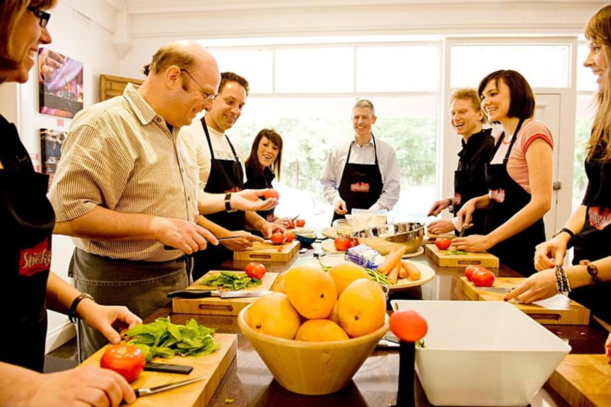 um grupo de pessoas em pé ao redor de uma cozinha preparando comida