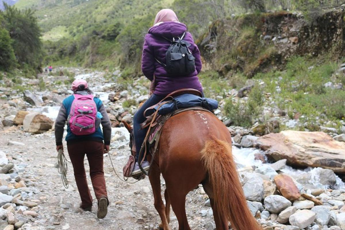 dues persones muntant a cavall per un camí rocós