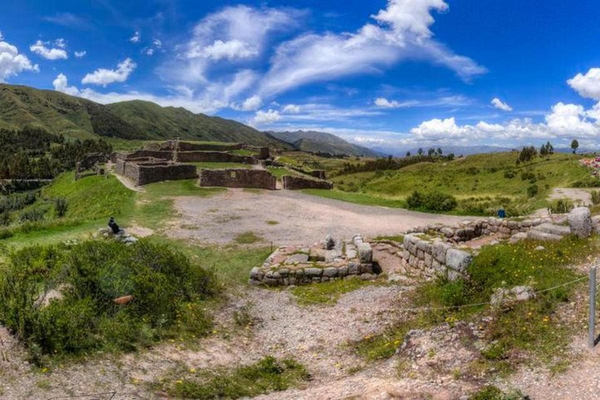 an old stone building in a field with mountains
