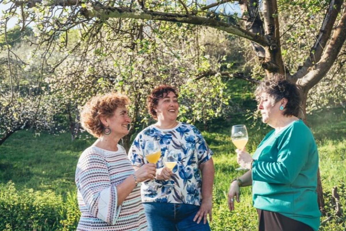 três mulheres em pé uma ao lado da outra segurando taças de vinho