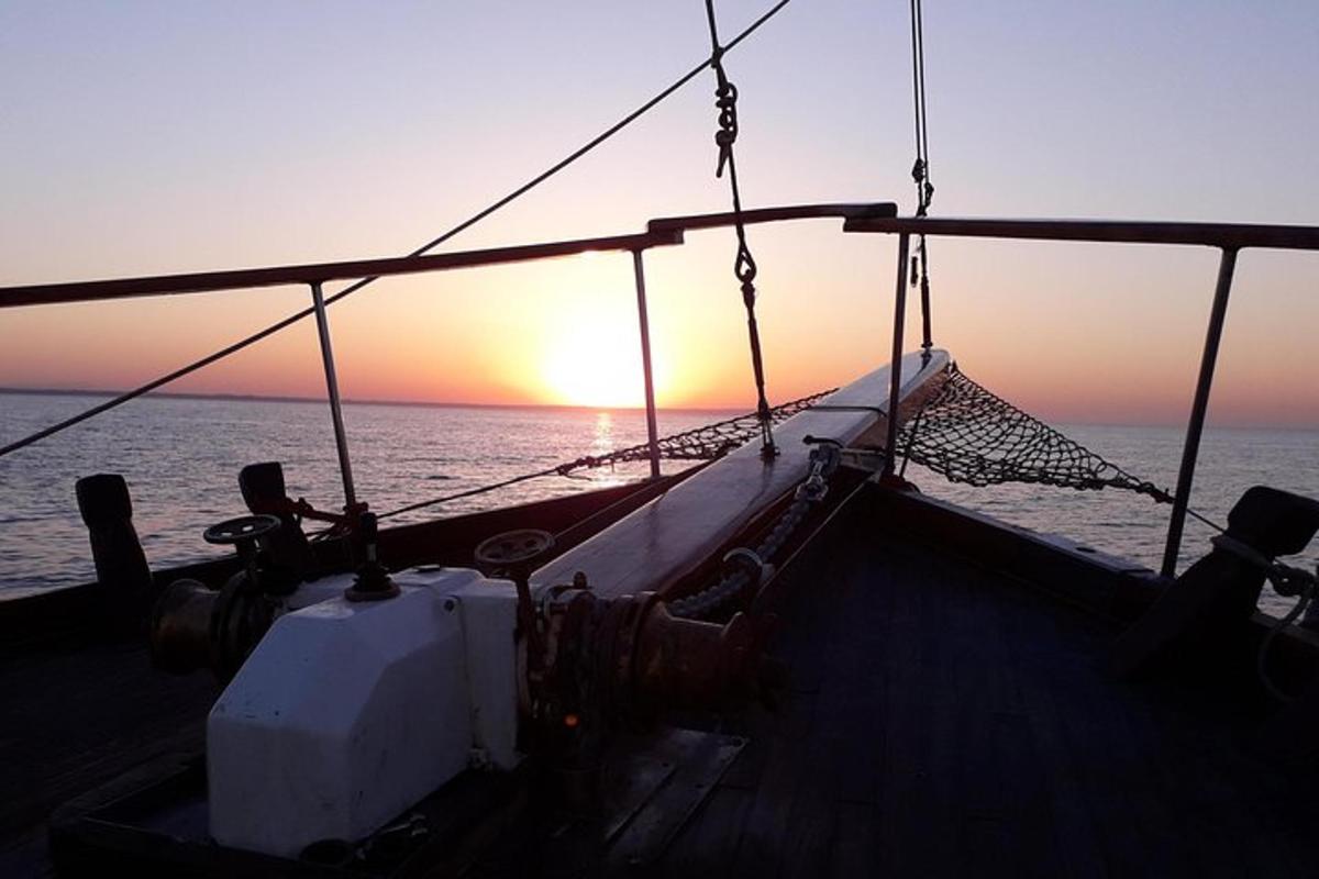 łódź na oceanie z zachodem słońca w tle