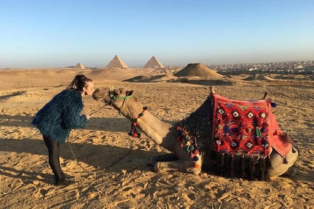 žena stojící vedle velblouda v pyramidách