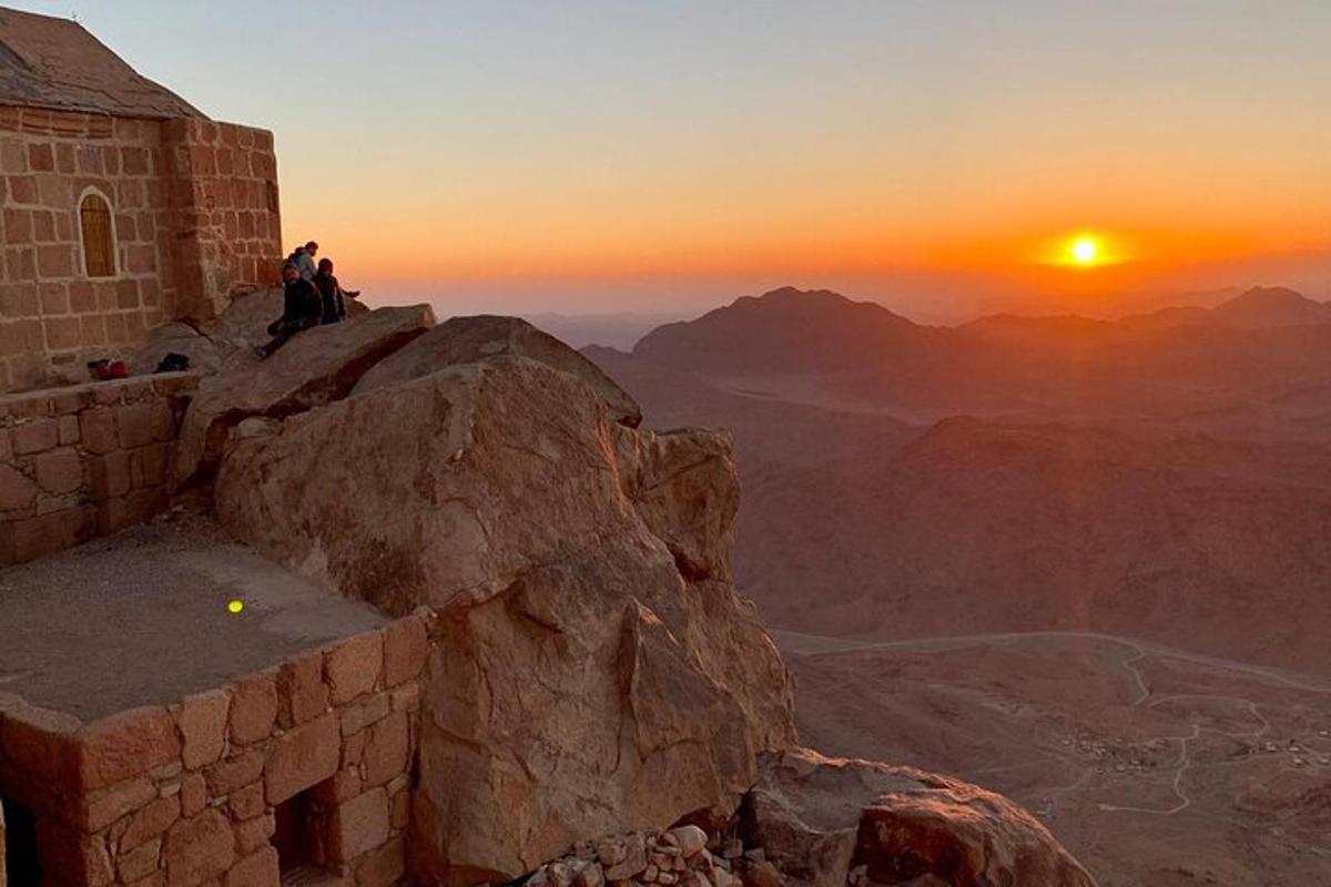 due persone sedute in cima a una montagna al tramonto