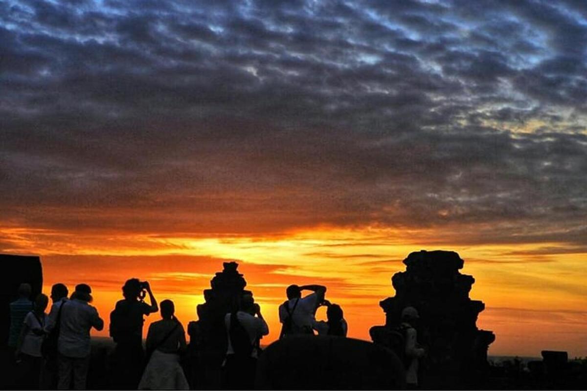 um grupo de pessoas em pé em frente ao pôr do sol