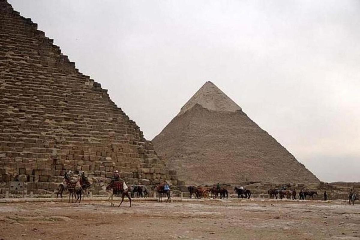 Skupina lidí na koních před pyramidami