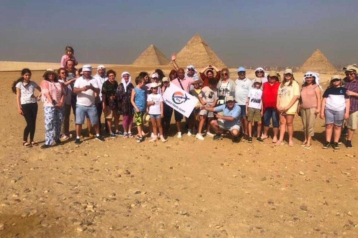 Skupina lidí pózuje pro fotografii před pyramidami
