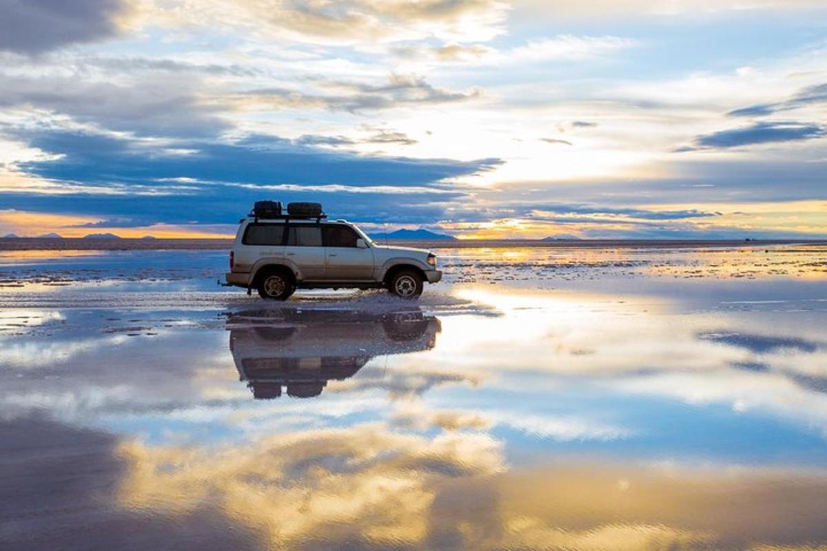 a white car parked on a beach with the sky