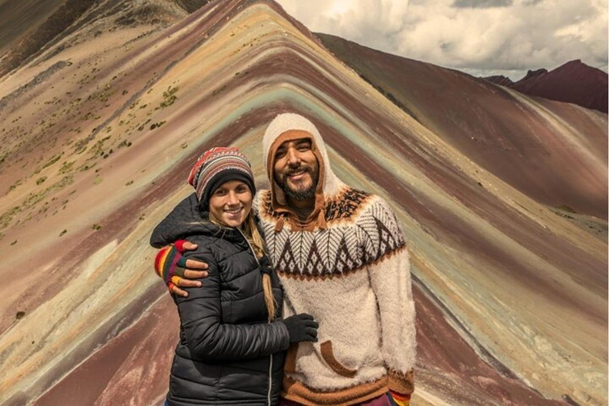 Un hombre y una mujer de pie frente a una pintura de una montaña.