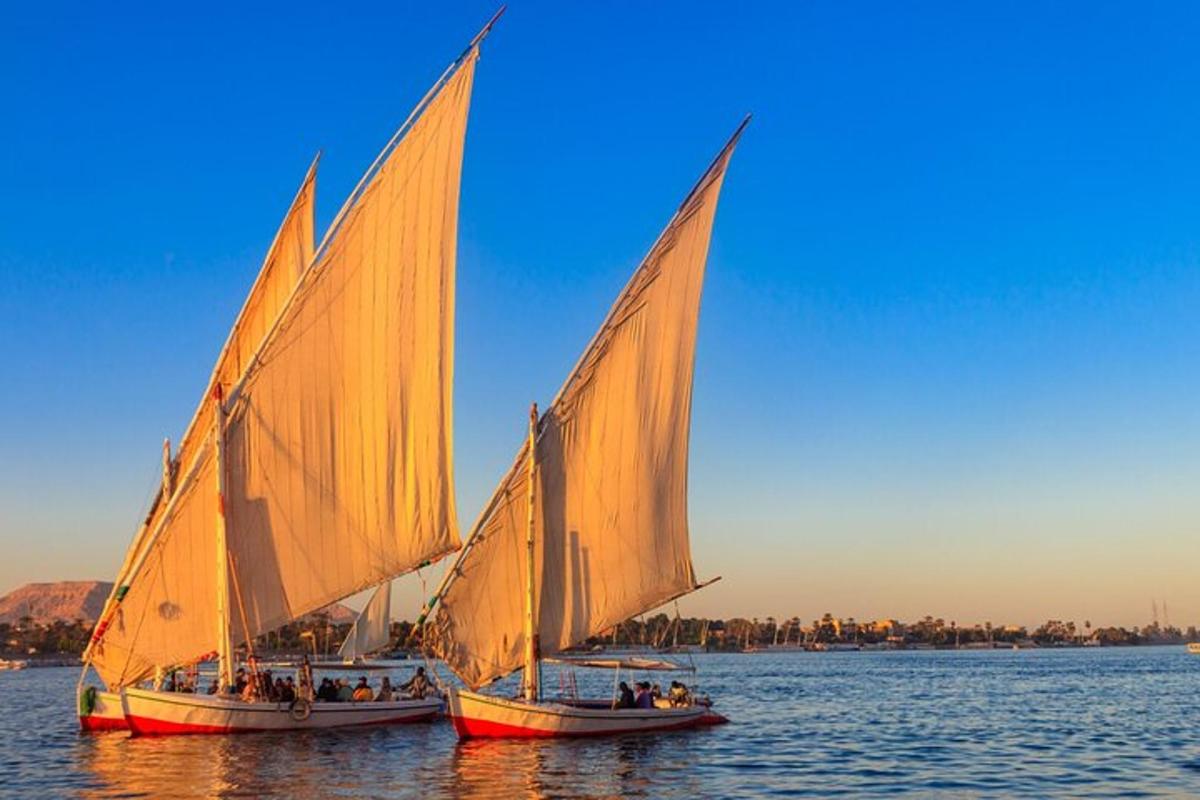 twee boten met oranje zeilen in het water