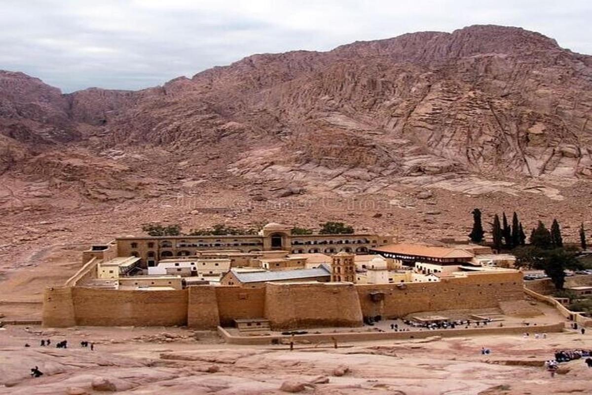 a building in the desert with a mountain in the background