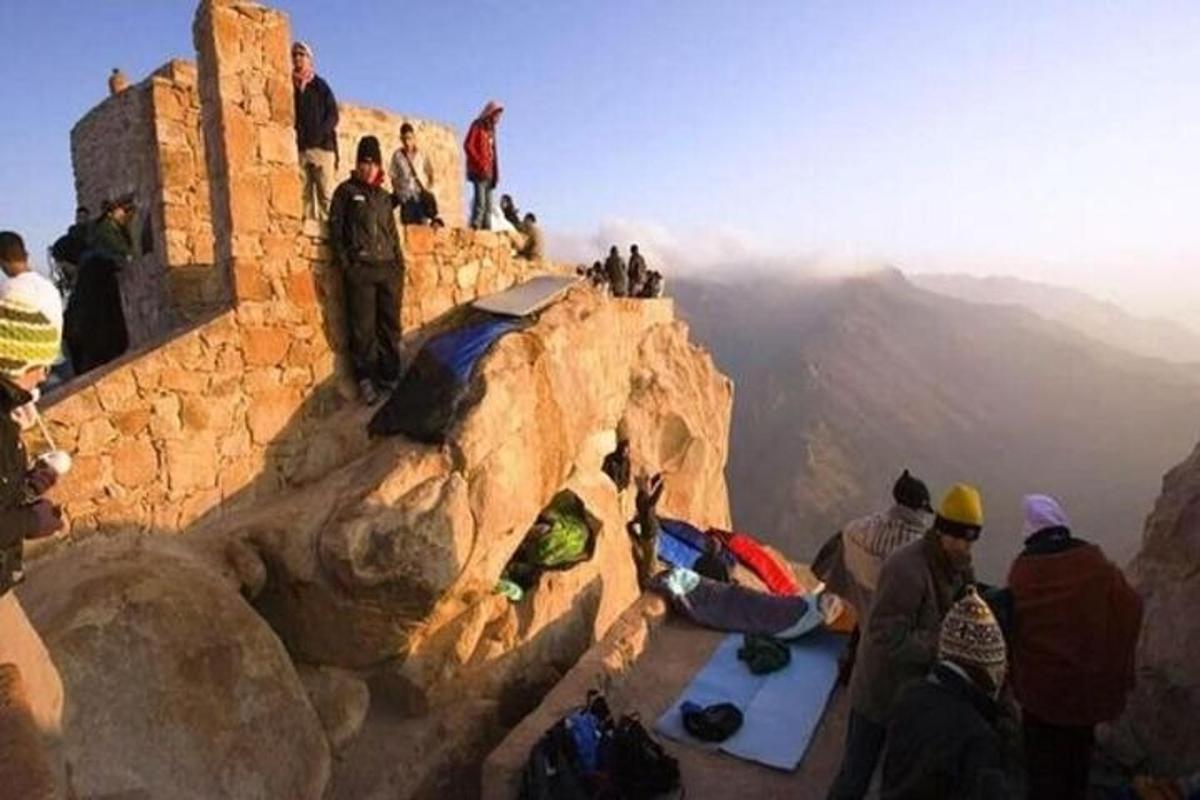 un grupo de personas sentadas en el borde de una montaña
