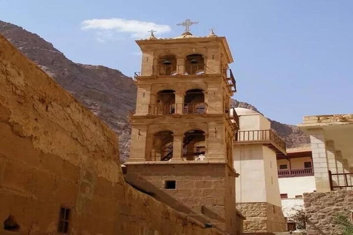 Un edificio con una torre de reloj al lado de una montaña.