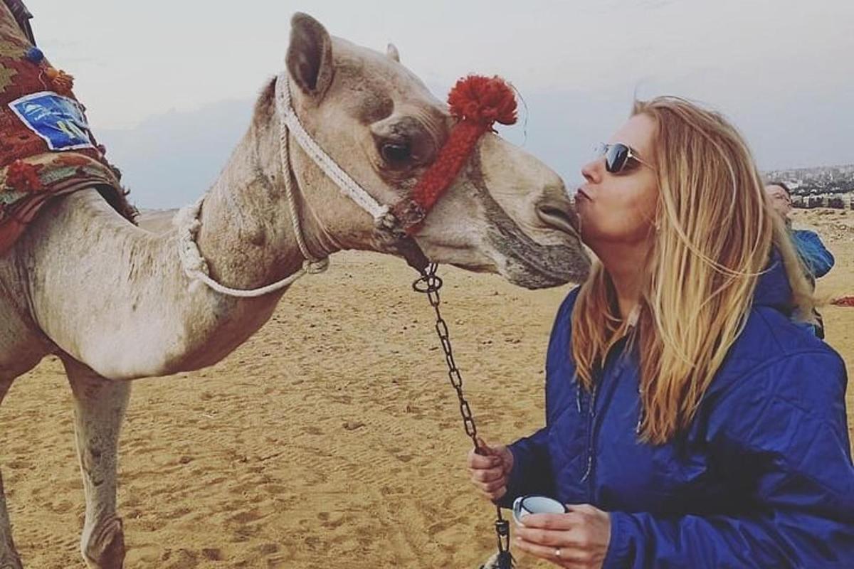una dona besa un camell a la platja