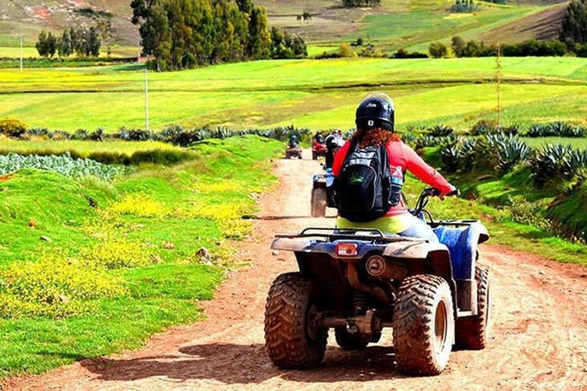 una persona que viaja en un vehículo de cuatro ruedas por un camino de tierra