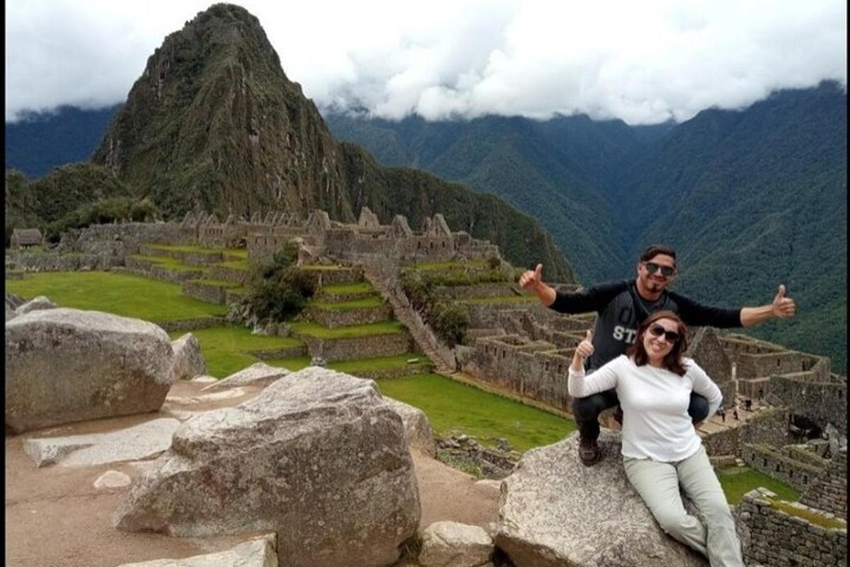 un homme et une femme assis sur un rocher avec une montagne