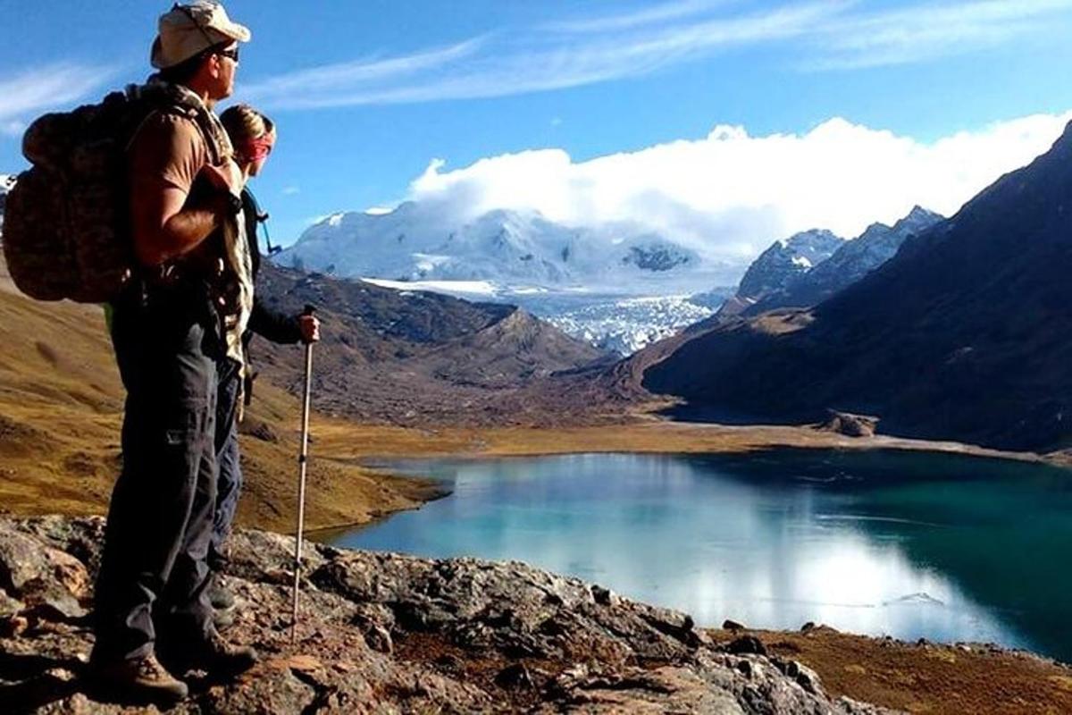Tveir menn standa á fjallstindi með útsýni yfir vatn