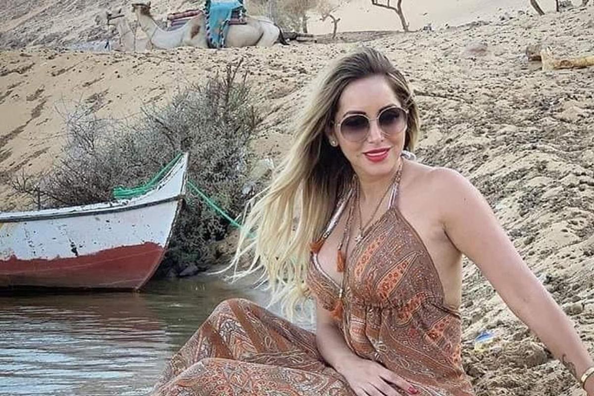 una mujer sentada en una playa junto a un barco