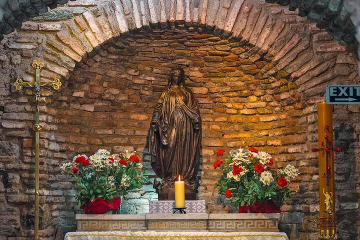 una statua in una chiesa con fiori e una candela