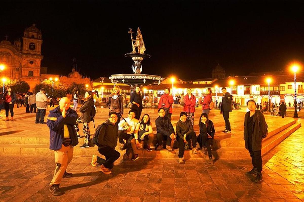 um grupo de pessoas caminhando ao redor de uma praça à noite