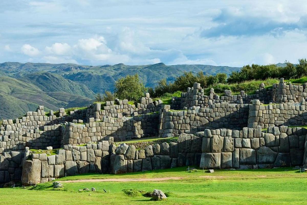 um grande muro de pedra em um campo com montanhas ao fundo