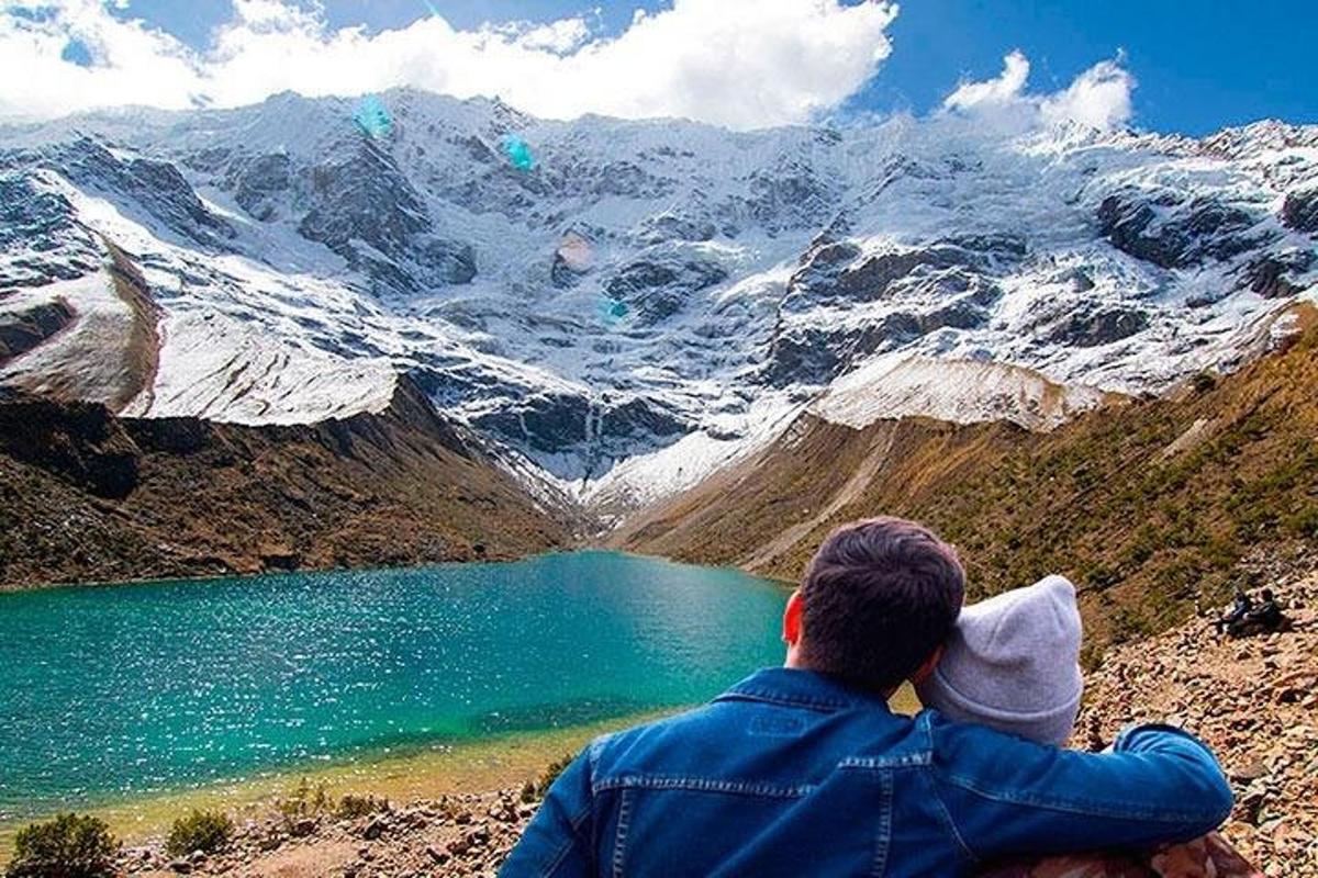 un uomo seduto in cima a una montagna che guarda un lago
