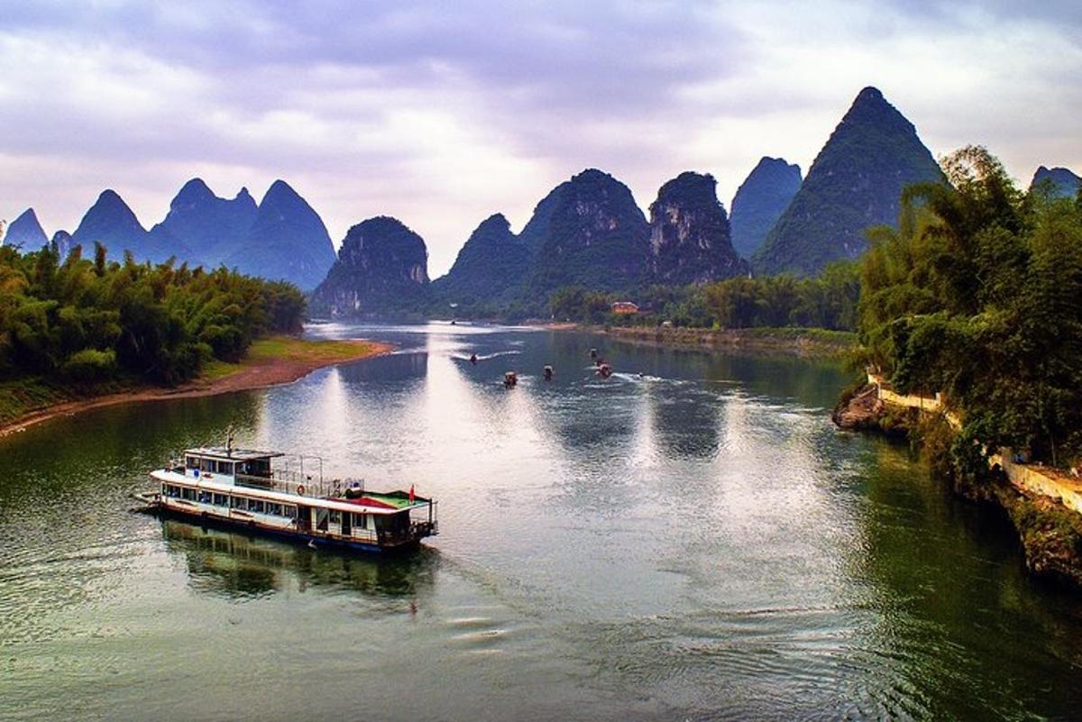 Un barco en un río con montañas al fondo.