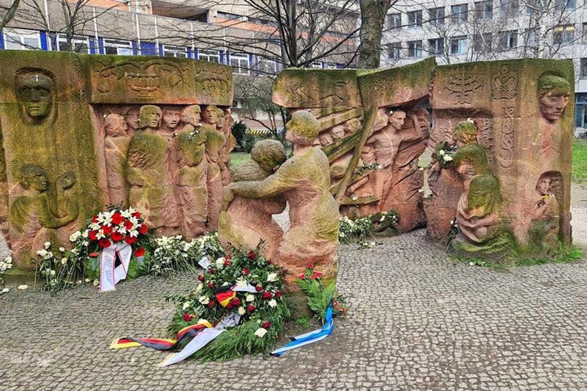 žmonių statula su gėlėmis priešais ją