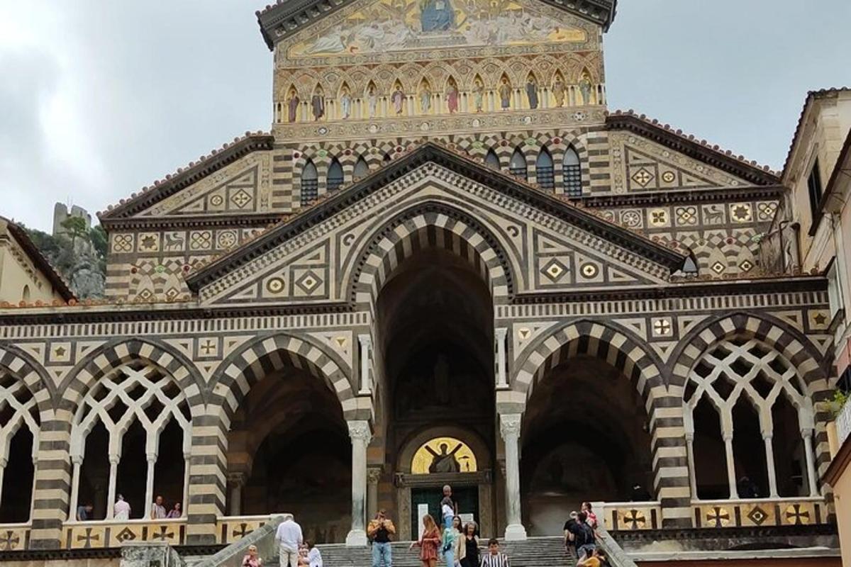 un grande edificio con una torre dell'orologio e persone che camminano intorno ad essa