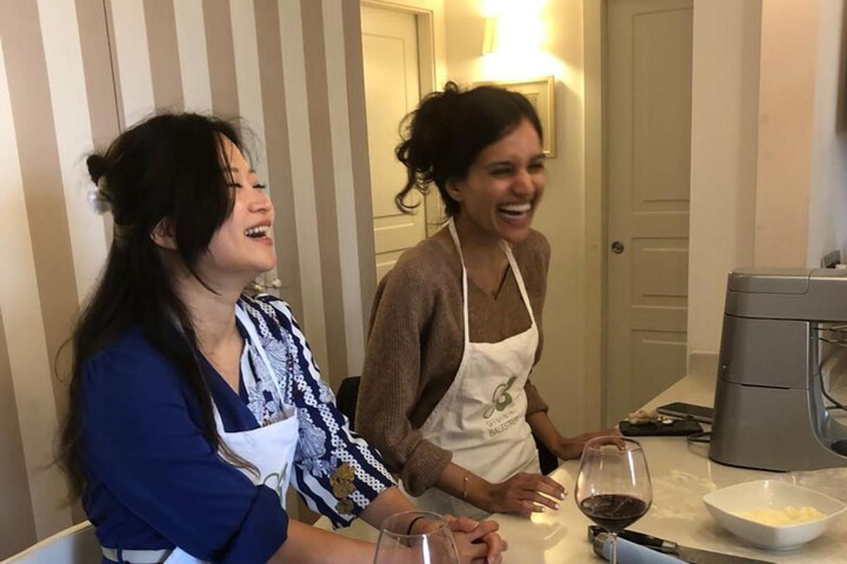 due donne in piedi al bancone della cucina con dei bicchieri di vino